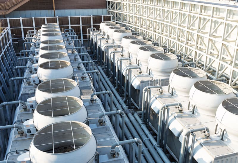Long row of cooling tower units with blue distribution pipework.